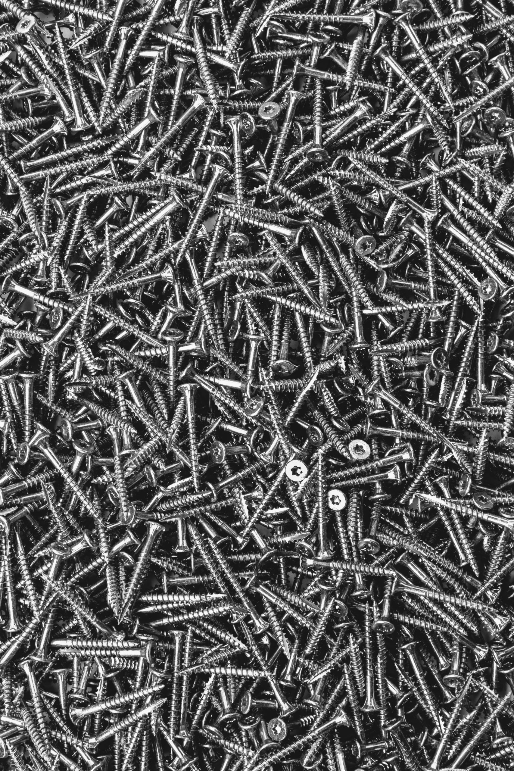 A large heap of grey metal screws, nails with a screw thread.